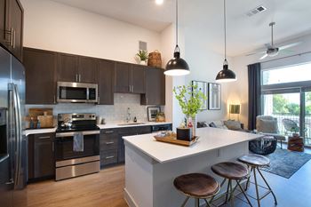 A kitchen and living room with a white island and stools
